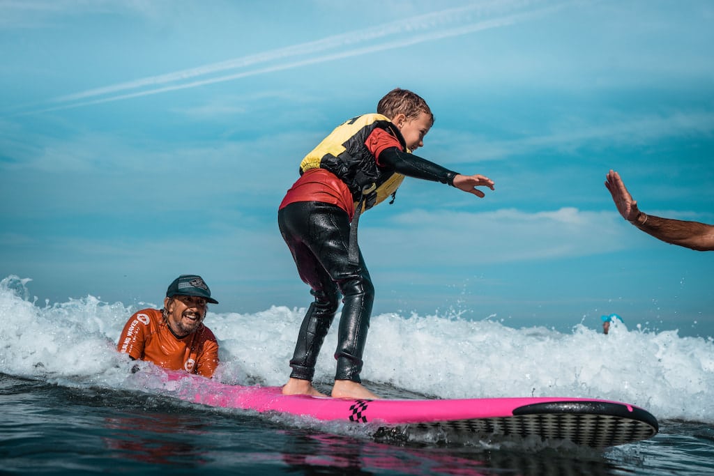 Child learning to surf with instructor's guidance.