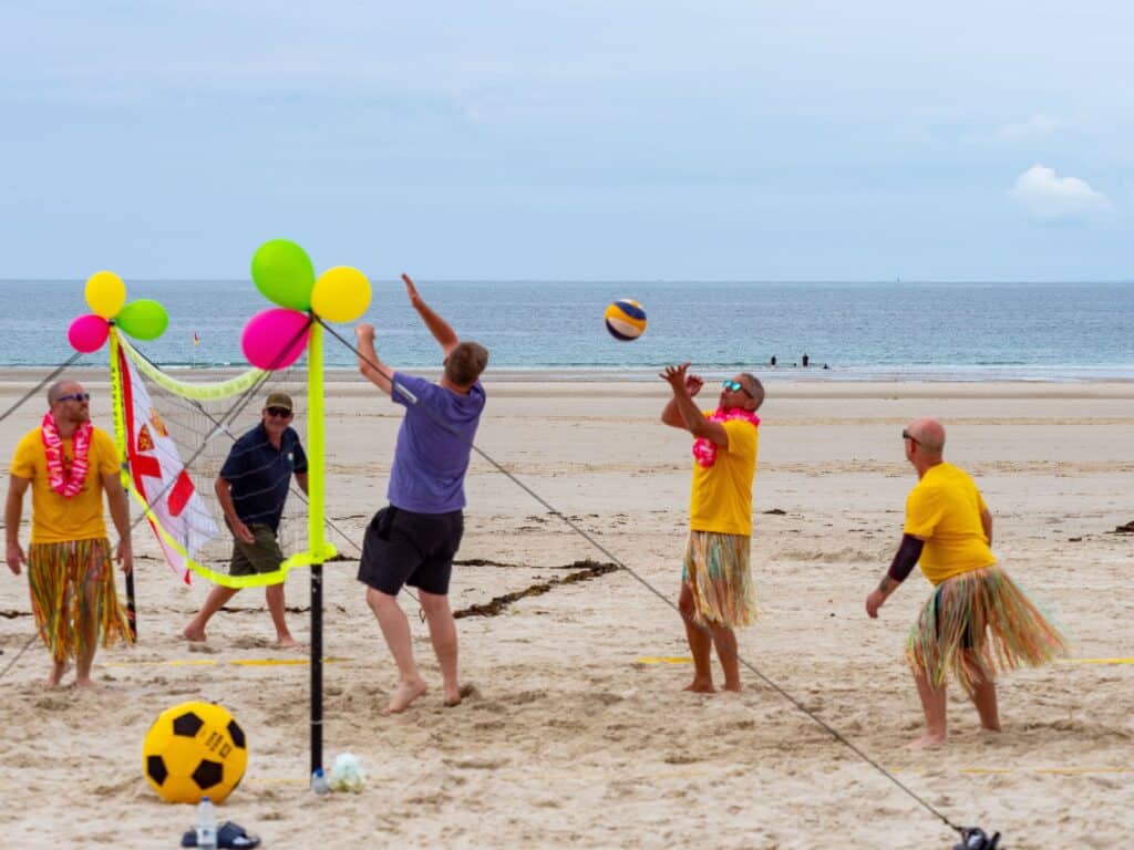 People playing beach volleyball with colourful balloons.