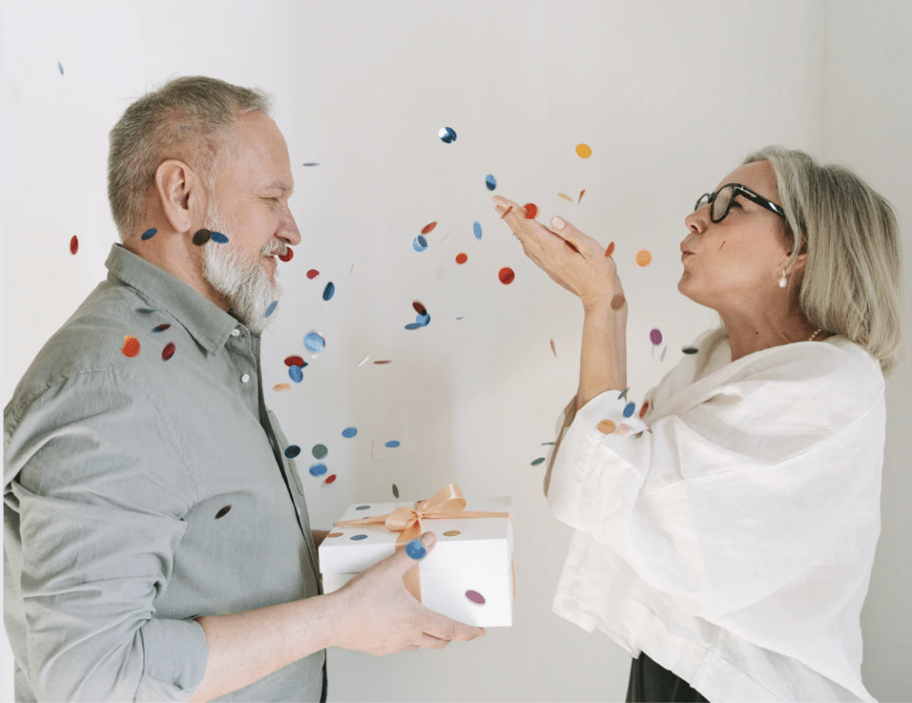 Elderly couple celebrating with confetti and gift.