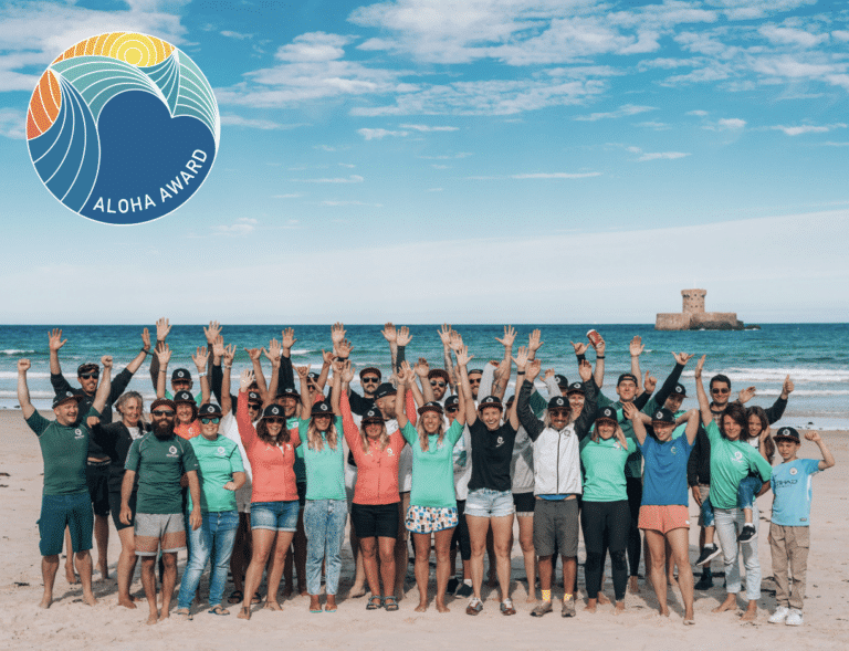 Group celebrating on beach with Aloha Award logo.