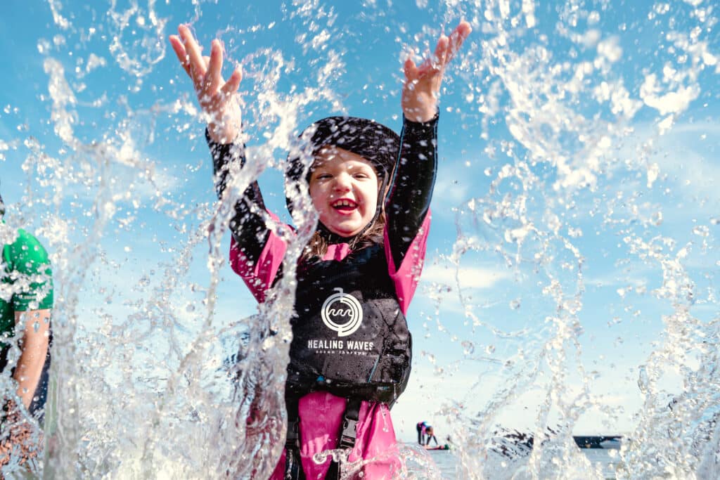 Child splashing in water wearing a buoyancy aid.